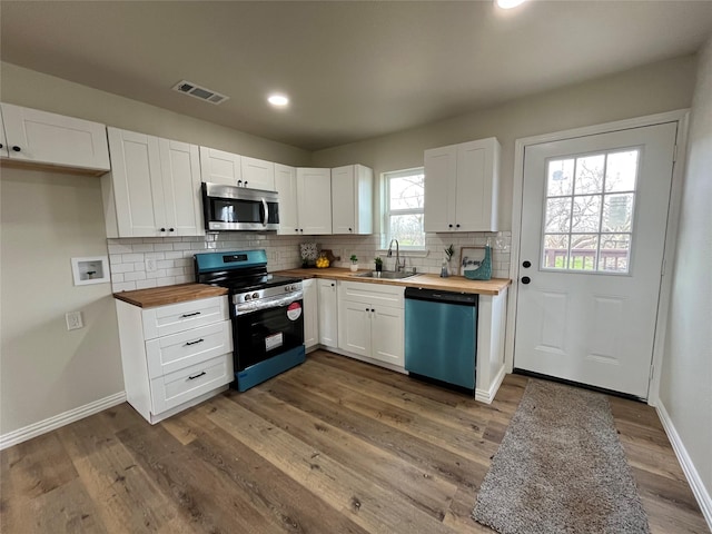 kitchen with visible vents, a sink, tasteful backsplash, appliances with stainless steel finishes, and butcher block counters