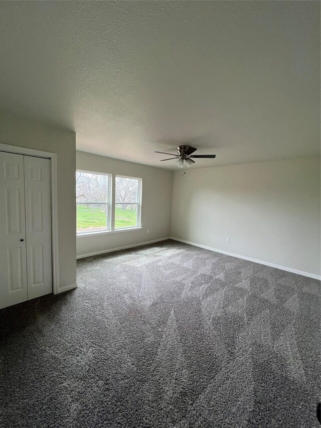 unfurnished room with carpet flooring, baseboards, and a textured ceiling