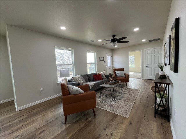 living area featuring a wealth of natural light, visible vents, baseboards, and wood finished floors