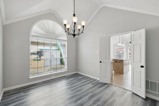 empty room with vaulted ceiling, wood finished floors, visible vents, and baseboards