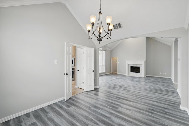 unfurnished living room featuring visible vents, baseboards, wood finished floors, and a tiled fireplace