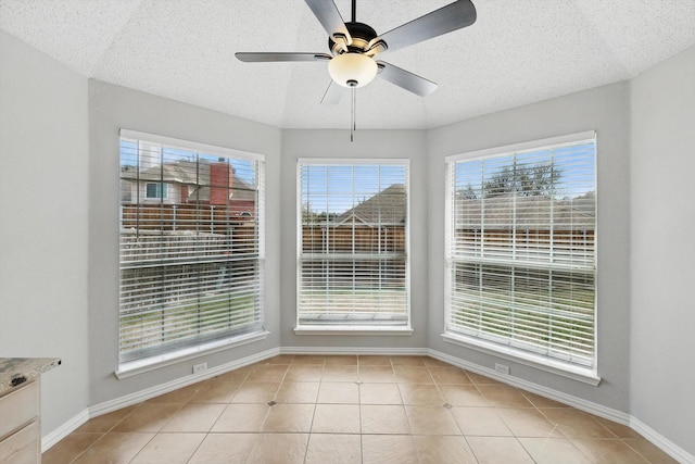 unfurnished dining area featuring light tile patterned floors, a textured ceiling, baseboards, and a ceiling fan