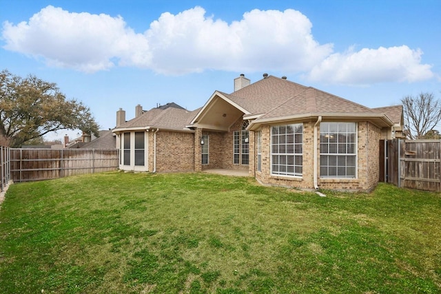 rear view of property featuring brick siding, roof with shingles, a yard, a fenced backyard, and a patio