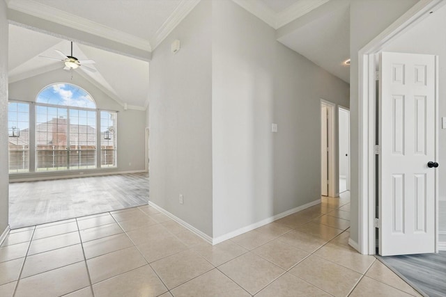 spare room with ornamental molding, light tile patterned floors, baseboards, ceiling fan, and vaulted ceiling