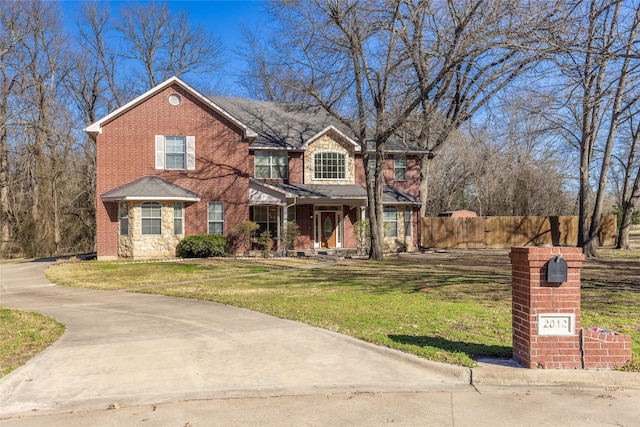 view of front of home featuring brick siding, a front yard, fence, and stone siding