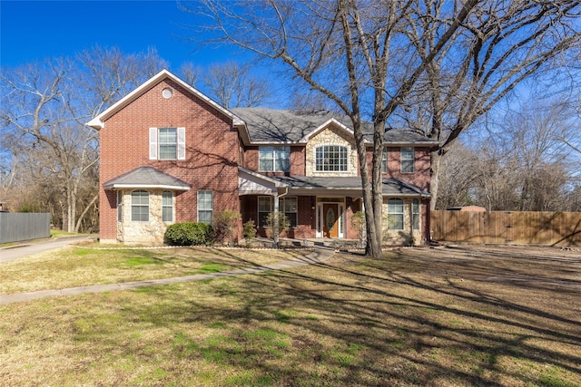 traditional home with a front lawn, a gate, fence, and brick siding