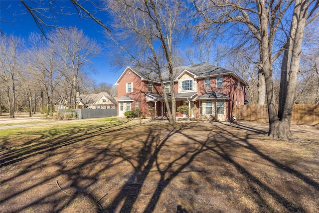 view of front of house featuring brick siding, a front lawn, and fence