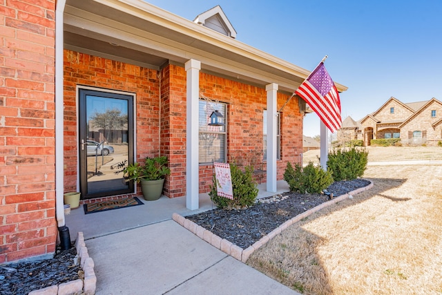 doorway to property featuring brick siding and covered porch