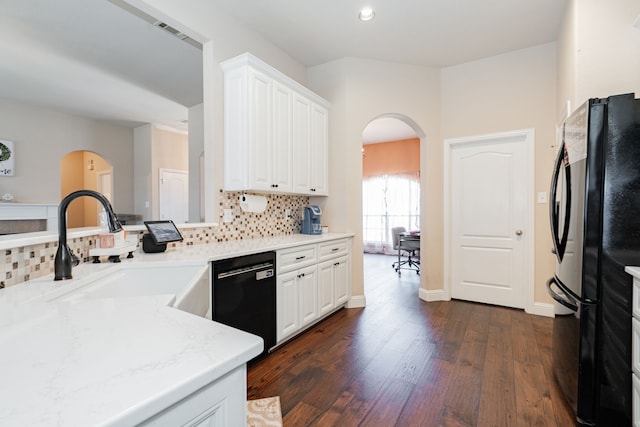 kitchen featuring decorative backsplash, black appliances, arched walkways, and a sink