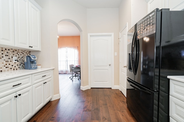 kitchen featuring dark wood-type flooring, tasteful backsplash, white cabinetry, arched walkways, and black refrigerator with ice dispenser