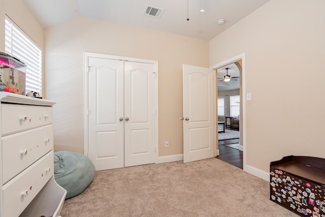 carpeted bedroom featuring lofted ceiling, visible vents, a closet, and baseboards