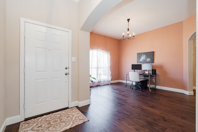 foyer featuring arched walkways, a chandelier, dark wood finished floors, and baseboards