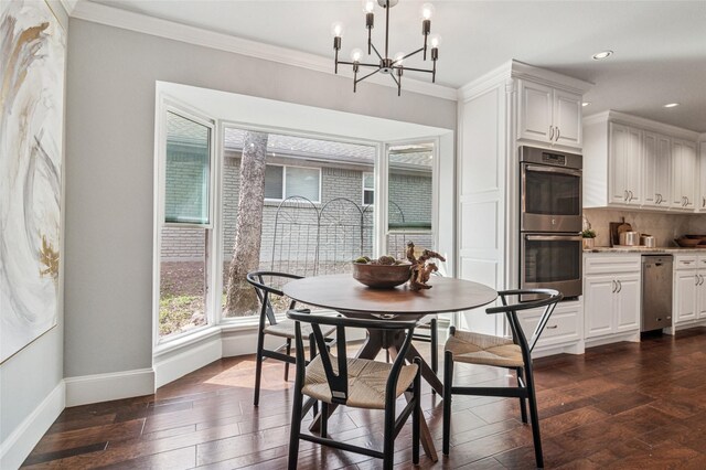 dining space featuring dark wood finished floors, crown molding, baseboards, and an inviting chandelier