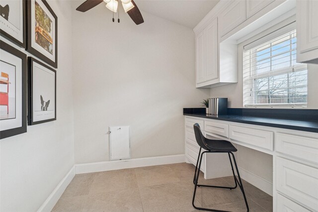 office area with light tile patterned floors, baseboards, and built in desk