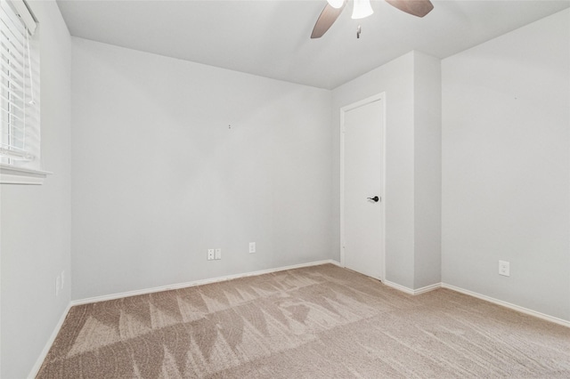 carpeted spare room featuring a ceiling fan and baseboards