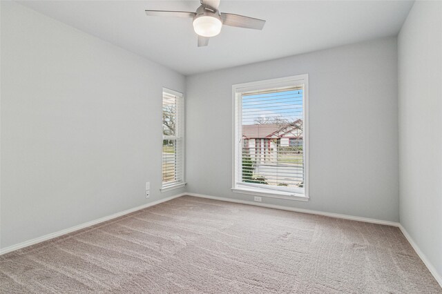 carpeted empty room with a ceiling fan and baseboards