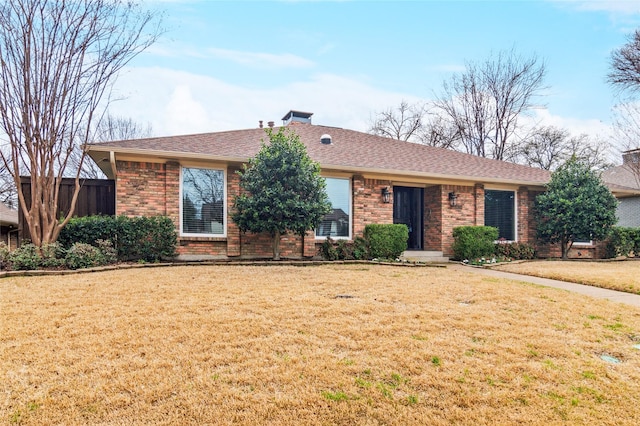 ranch-style house with brick siding, a chimney, a front lawn, and roof with shingles