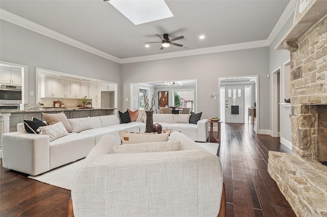 living room featuring baseboards, ornamental molding, recessed lighting, a skylight, and dark wood-style flooring