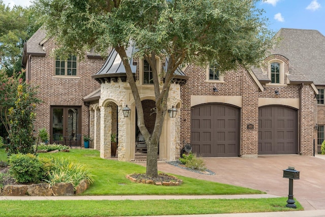 view of front facade featuring a front yard, driveway, an attached garage, stone siding, and brick siding