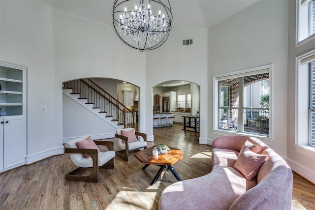 living area featuring visible vents, wood finished floors, stairway, arched walkways, and baseboards