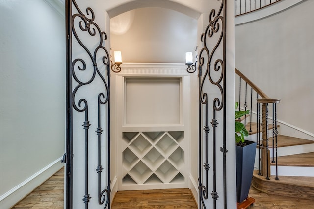 interior space featuring arched walkways, baseboards, and wood finished floors