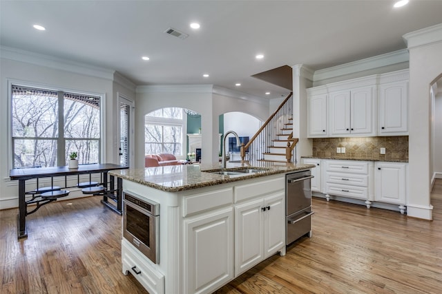 kitchen featuring visible vents, a sink, dark stone countertops, tasteful backsplash, and a fireplace