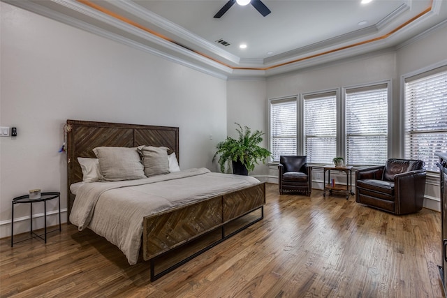 bedroom with multiple windows, a raised ceiling, and wood finished floors