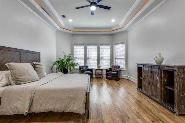 bedroom with visible vents, crown molding, a raised ceiling, and wood finished floors