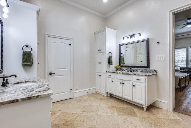 full bath with a sink, two vanities, baseboards, and ornamental molding