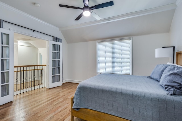 bedroom with wood finished floors, ornamental molding, vaulted ceiling, french doors, and a baseboard heating unit