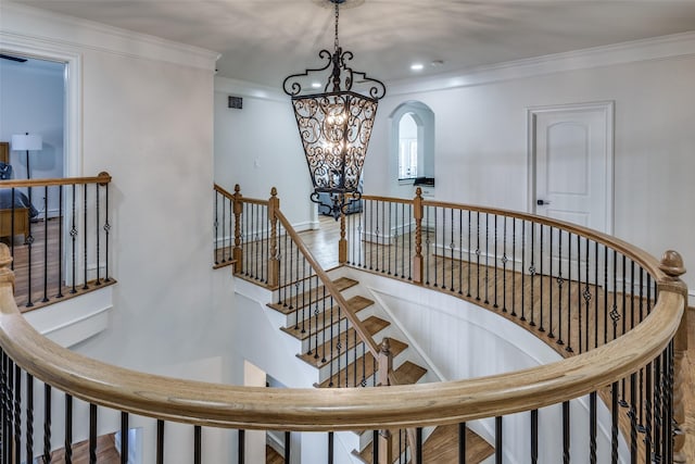 stairway with recessed lighting, crown molding, an inviting chandelier, and wood finished floors