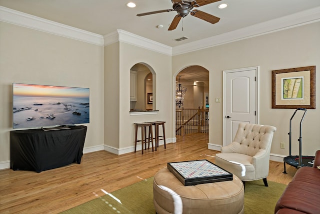 living room with visible vents, arched walkways, wood finished floors, and crown molding