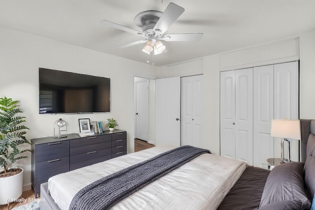 bedroom with ceiling fan, multiple closets, and wood finished floors