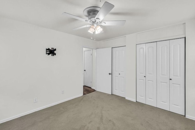 unfurnished bedroom featuring baseboards, a ceiling fan, carpet, and multiple closets