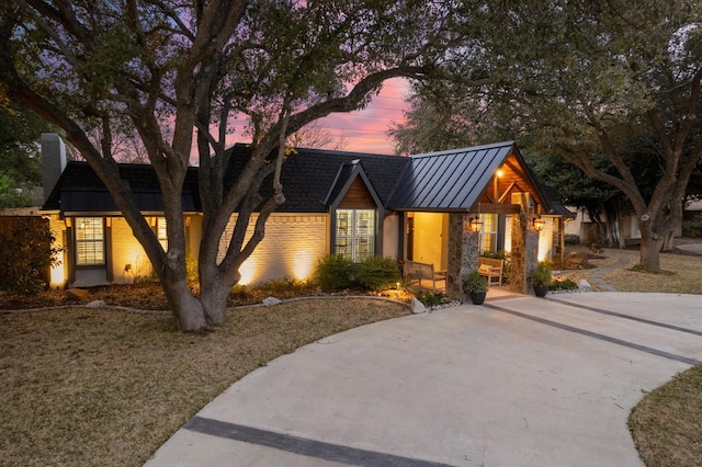 view of front of property with a standing seam roof, stone siding, and metal roof