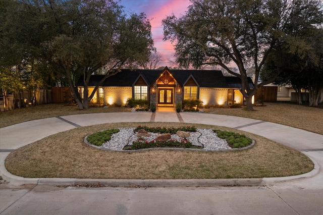 view of front of property with a lawn, french doors, fence, and curved driveway