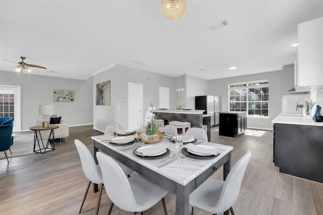 dining room with a ceiling fan, wood finished floors, visible vents, and baseboards