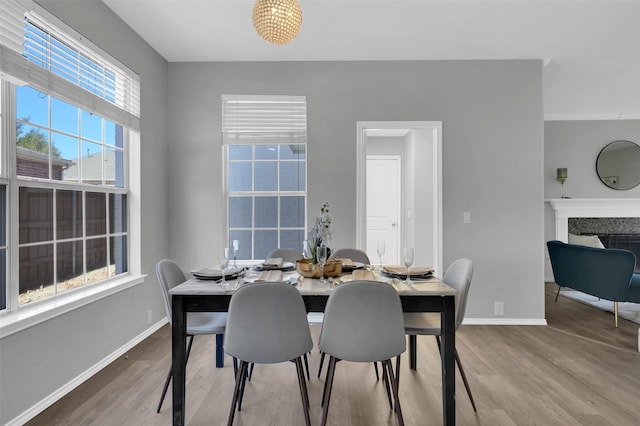 dining area with baseboards, wood finished floors, and a fireplace