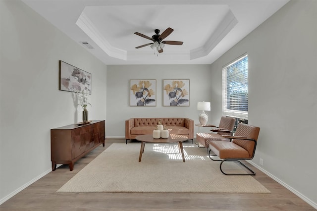 living room featuring visible vents, a raised ceiling, baseboards, and wood finished floors