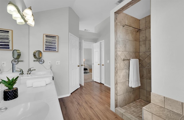 full bath with a tile shower, wood finished floors, and a sink