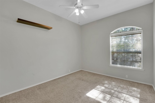 carpeted empty room featuring baseboards and a ceiling fan