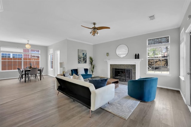 living area with baseboards, wood finished floors, visible vents, and a healthy amount of sunlight