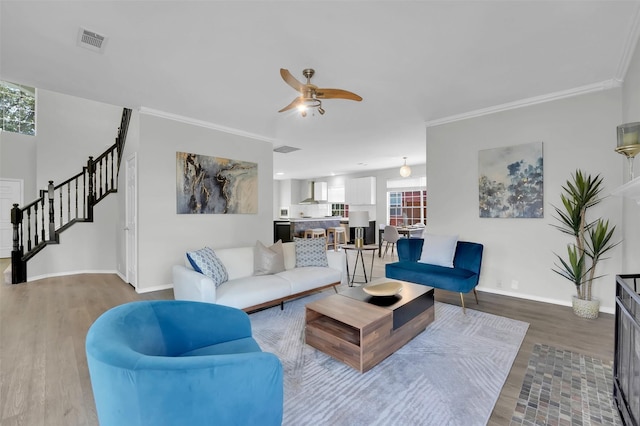 living area with visible vents, wood finished floors, and crown molding