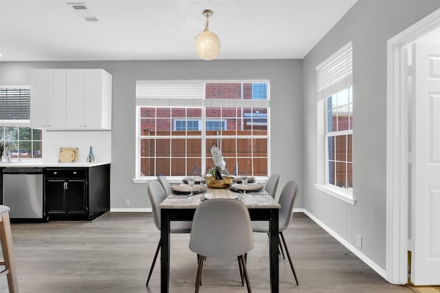 dining space with visible vents, light wood-type flooring, and baseboards