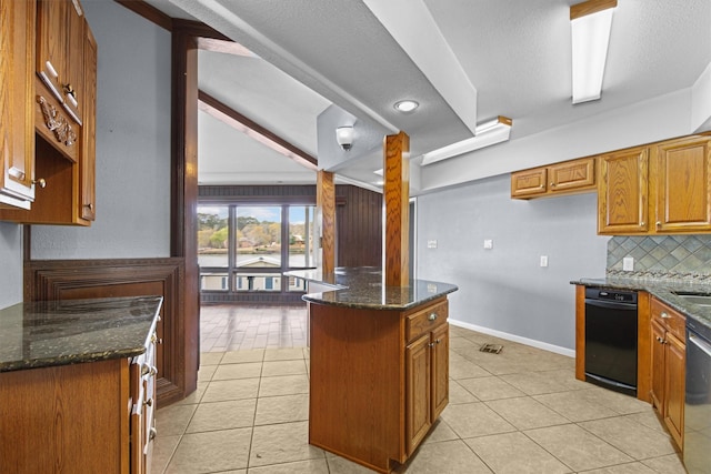 kitchen featuring brown cabinets, backsplash, a kitchen island, dark stone counters, and light tile patterned flooring