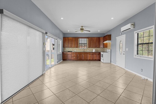 kitchen with an AC wall unit, white range with electric cooktop, a sink, tasteful backsplash, and light tile patterned floors