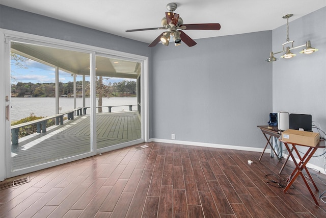 interior space featuring visible vents, a water view, baseboards, and dark wood-style flooring