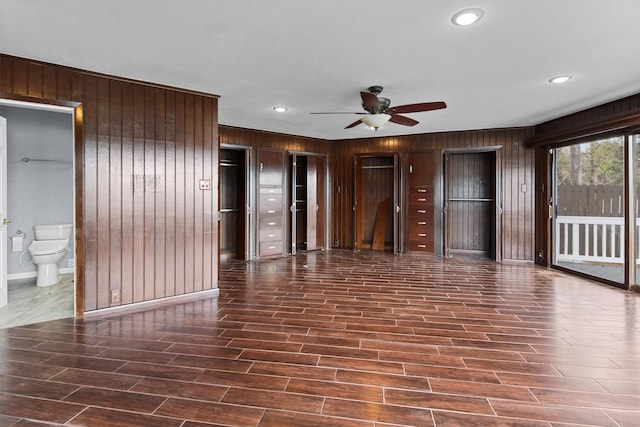 unfurnished living room featuring wood finish floors, baseboards, wood walls, recessed lighting, and a ceiling fan