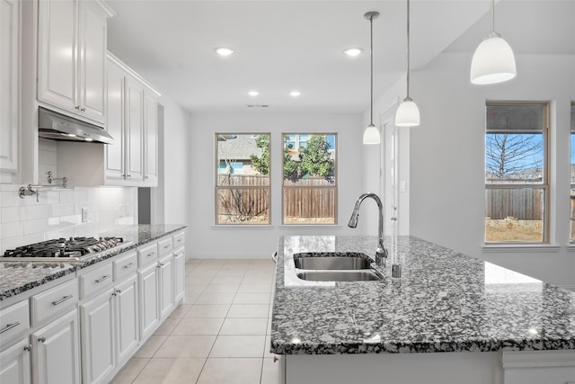 kitchen with stainless steel gas cooktop, a sink, under cabinet range hood, white cabinetry, and backsplash