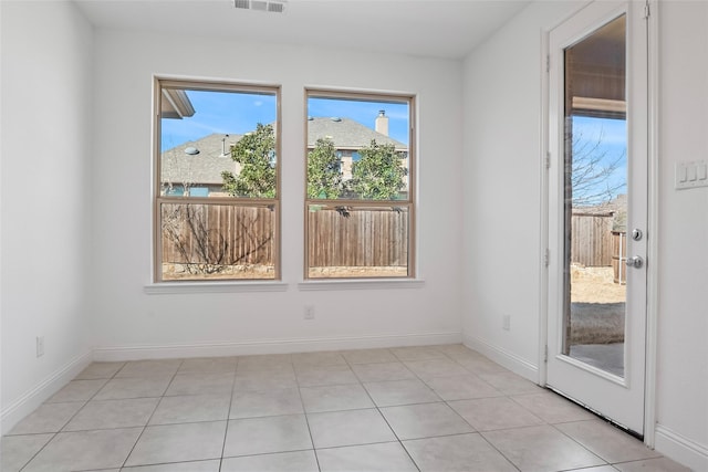 spare room featuring light tile patterned floors, visible vents, and baseboards